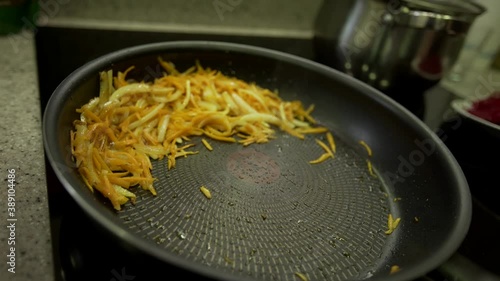Sliced onion and carrot pieces fried on a pan close-up. Frying onions and carrot in sunflower oil in a hot pan