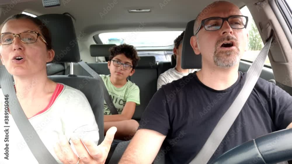 Escaping home life, driving to new destinations. A Caucasian family is in the car in line to reach the holiday destination: the parents are cheerful and sing while the perplexed children watch. Escaping home life, driving to new destinations. A Caucasian family is in the car in line to reach the holiday destination: the parents are cheerful and sing while the perplexed children watch.