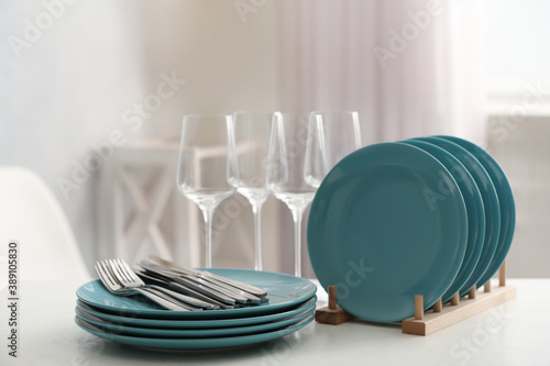 Set of clean dishes, cutlery and wineglasses on white table indoors