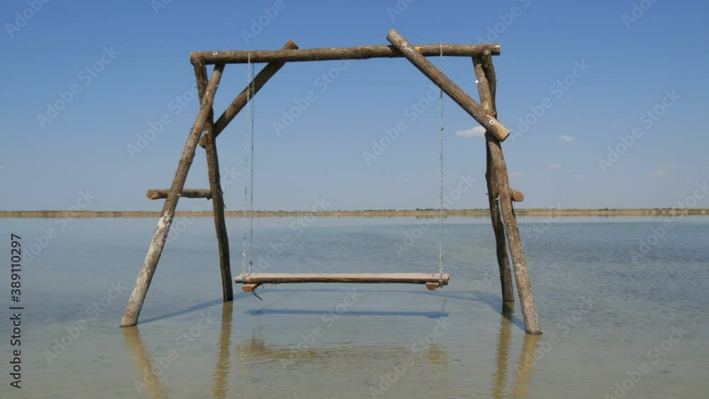 A lonely Wooden swing on the water is picturesquely located on a salt lake, recreation relax concept. A lonely Wooden swing on the water is picturesquely located on a salt lake, recreation relax concept.