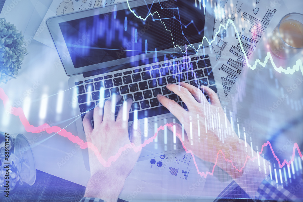 Double exposure of man's hands typing over laptop keyboard and forex chart hologram drawing. Top view. Financial markets concept. Double exposure of man's hands typing over laptop keyboard and forex chart hologram drawing. Top view. Financial markets concept.