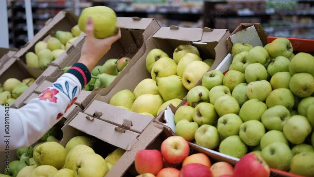 Young Woman Buying Fruits in a Grocery Store. Choosing Fresh Pears. Concept of Healthy Organic Food Young Woman Buying Fruits in a Grocery Store. Choosing Fresh Pears. Concept of Healthy Organic Food