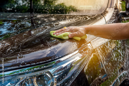 Car care service worker under car wash cleaning at garage. photo