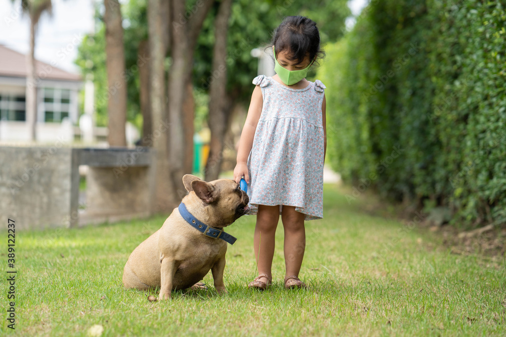 little girl wearing healthy face mask to prevent virus and pm2.5 walk the dog outdoor. little girl wearing healthy face mask to prevent virus and pm2.5 walk the dog outdoor.