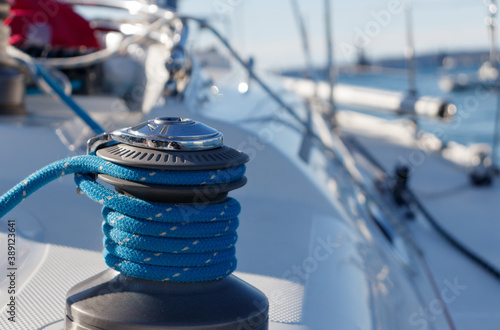Defocused view of a yacht, with a winch and white on blue sheet on foreground (selective focus) photo
