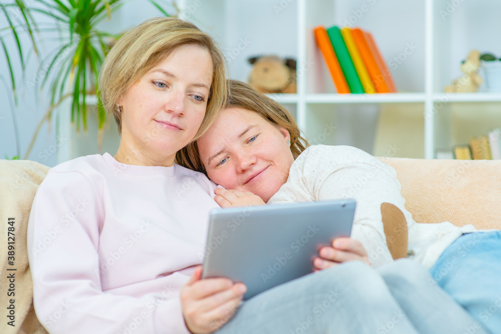 Two young women are lying on the couch at home and watching a movie on a tablet. Gay lesbian couple at home. Lesbian couple concept Two young women are lying on the couch at home and watching a movie on a tablet. Gay lesbian couple at home. Lesbian couple concept