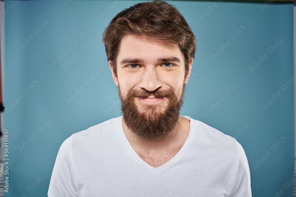 Bearded man displeased facial expression emotions close-up blue background white t-shirt Bearded man displeased facial expression emotions close-up blue background white t-shirt