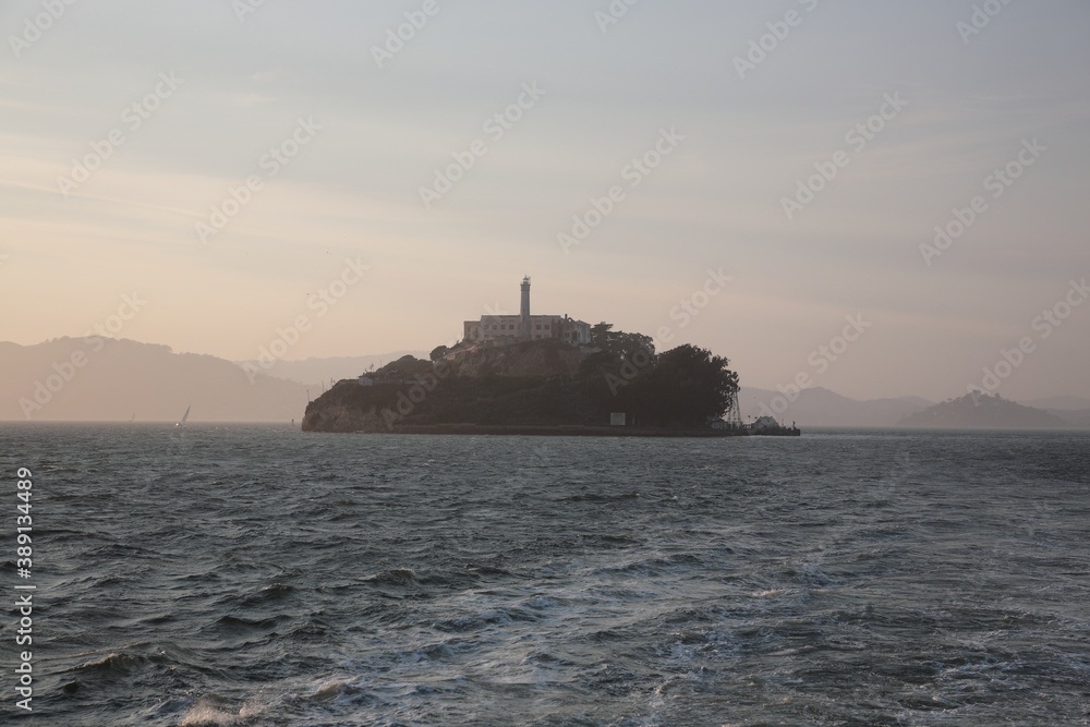 View of Alcatraz Island with prison and lighthouse under sunset in San Francisco, California, USA.