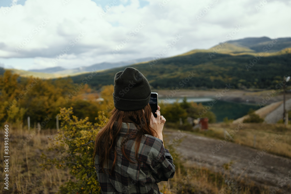 Traveler with a mobile phone in her hands on nature in autumn in the mountains Traveler with a mobile phone in her hands on nature in autumn in the mountains
