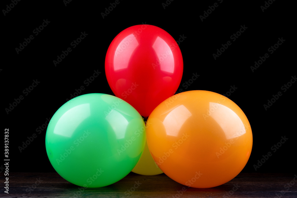 Bunch of colorful balloons on a wooden table against a black background. Bunch of colorful balloons on a wooden table against a black background.
