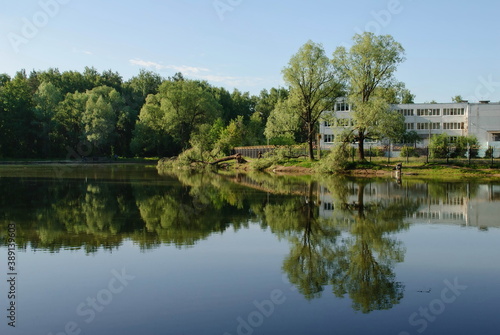 Ramenskoe. Moscow region. Russia. June 12. 2017. The school building is reflected in the water of a small pond on a Sunny morning.