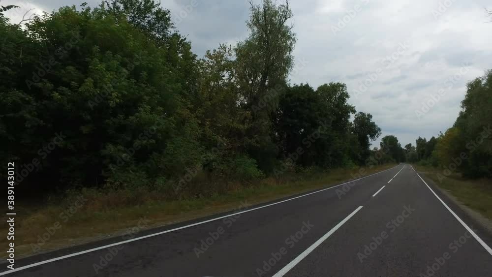 Late evening. Smooth asphalt road among abandoned rural houses in an abandoned village among dense trees Late evening. Smooth asphalt road among abandoned rural houses in an abandoned village among dense trees