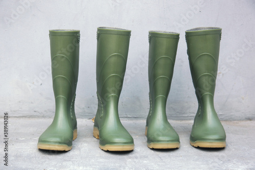 Row of Green rubber boots on cement background