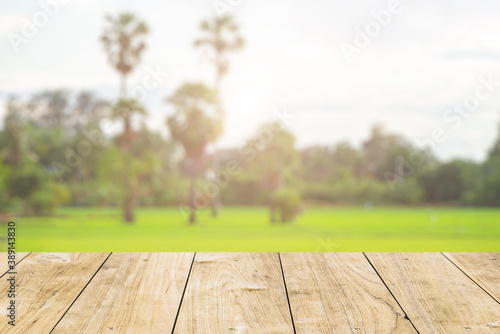 wooden table foreground with morning sunrise green rice field natural blur background for advertising agriculture products.