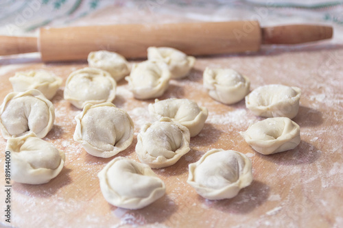 Closeup on semi-finished pelmeni dumplings on the wooden board.