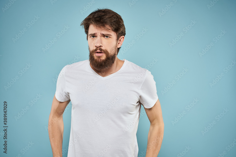 Man in white t-shirt lifestyle studio emotions facial expression blue isolated background Man in white t-shirt lifestyle studio emotions facial expression blue isolated background