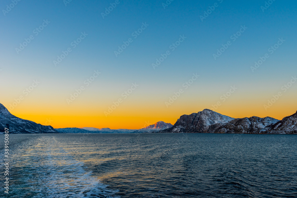 Amazing colorful sunset over Norwegian sea seen from small cruise ship MS Lofoten of Hurtigruten on clear winter day