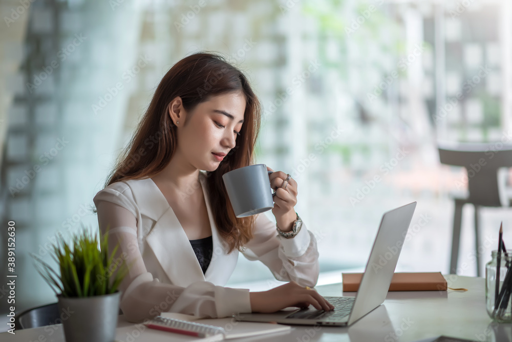 Young asian businesswoman on a coffee break and using laptop computer in office. Young asian businesswoman on a coffee break and using laptop computer in office.
