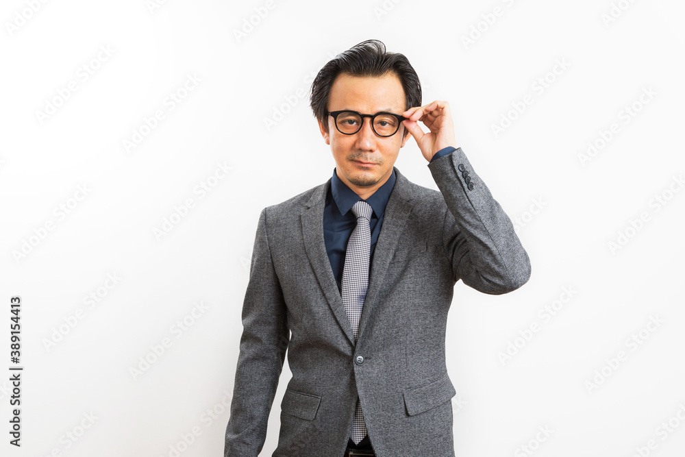 Confident Asian businessman in grey suit and eyeglasses posing standing over white wall background, Business success concept. Confident Asian businessman in grey suit and eyeglasses posing standing over white wall background, Business success concept.