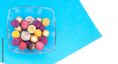handmade chocolate truffles, different colors on a platter on a blue and white background.