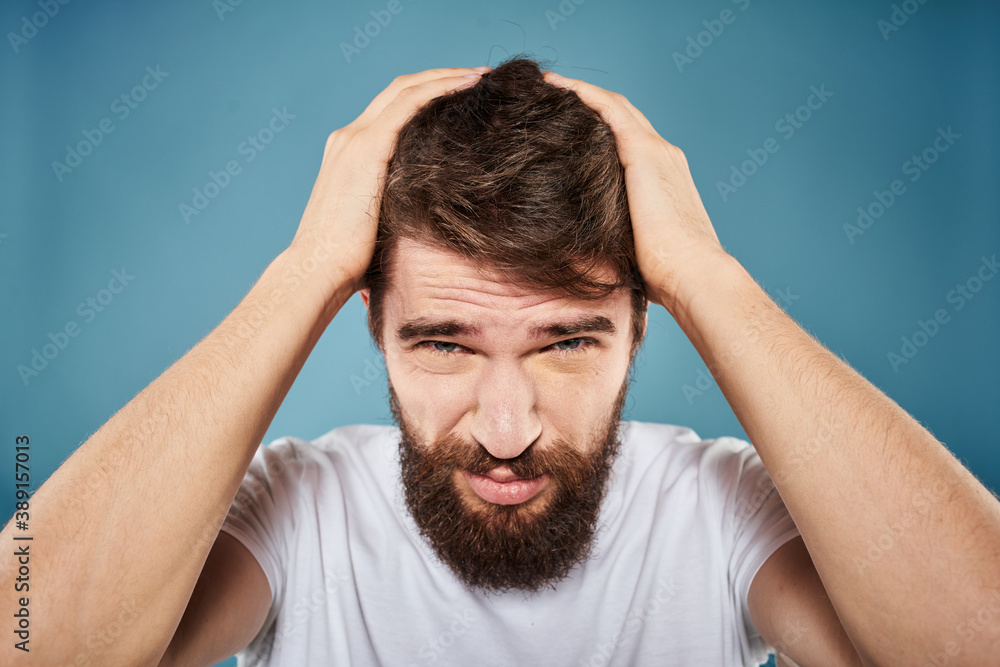Bearded man displeased facial expression emotions close-up blue background white t-shirt Bearded man displeased facial expression emotions close-up blue background white t-shirt