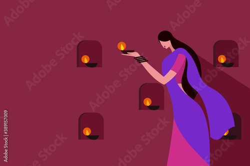 A woman wearing traditional dress lighting Diwali festival lamps