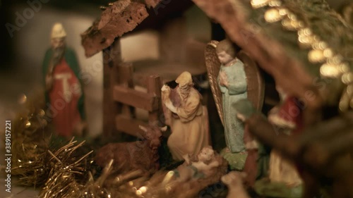 Woman puts miniature figurines of Mary and Joseph in a christmas crib. Beautiful nativity scene and christmas decorations - close view photo