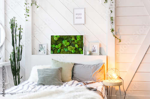 Interior light wall with a picture of moss, white walls, plants, candles and frames , bed , home and comfort