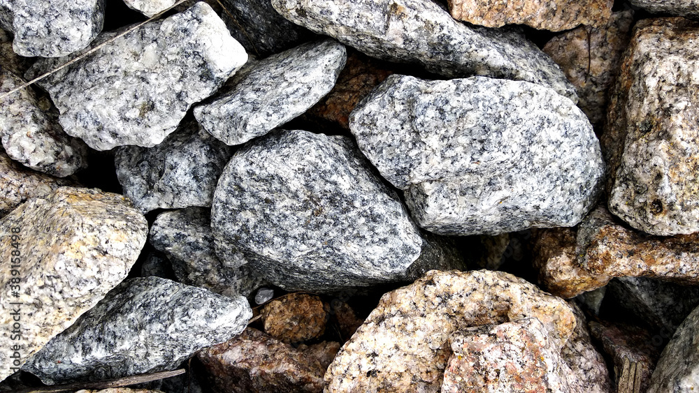 Macro photo of crushed stone and gravel on the ground. Texture background white gray stones on a black earth background.