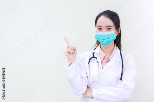 Asian woman doctor shows hand point on white background and wears medical face mask and face shield  in health care concept