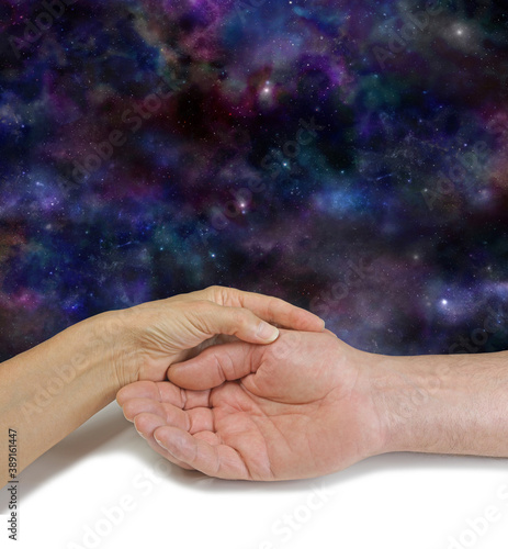 Palm Reading Cosmic Message Background - female hand holding man's open hand against a deep space night sky background with copy space for messages above
