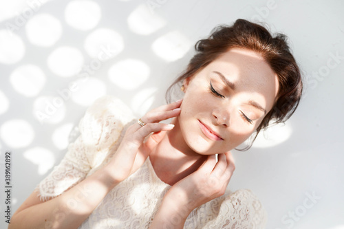 Close up portrait of woman with closed eyes enjoying sunlights on white background