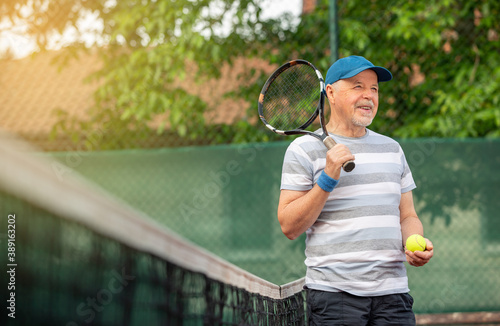 Smiling, sporting, active senior man playing tennis in the outdoor, sports pensioner, sport concept © Khaligo