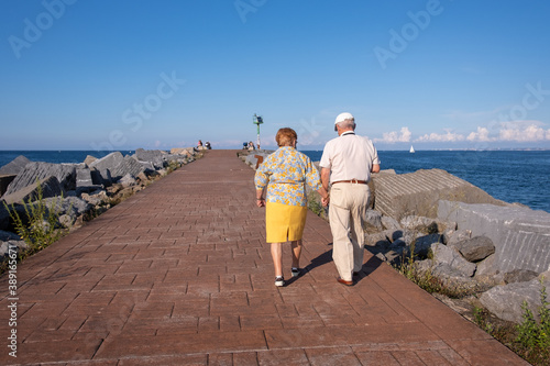 Senior couple walking by the sea. Aged people with a healthy lifestyle. Long lasting couple holding hands. Life expectancy is high in Spain. Hondarribia, Euskadi Basque country, North of Spain photo