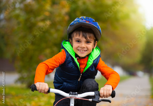 Portrait of a boy in the park. Small child wearing a helmet and cycling on an autumn day. Active healthy outdoor sports