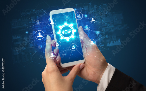 Photos Female hand holding smartphone with VOIP abbreviation, modern technology concept