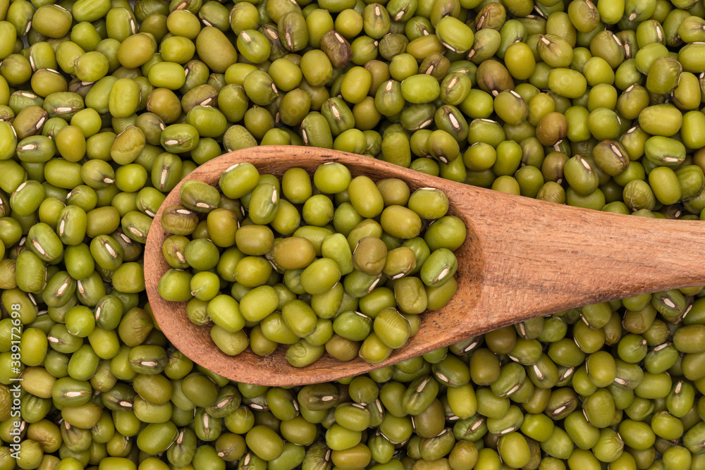 Mung beans in background and on wooden spoon seen directly from above covering the full frame Mung beans in background and on wooden spoon seen directly from above covering the full frame