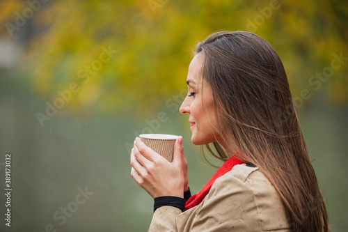 Brunette woman with cup of coffee in the autumn park.
