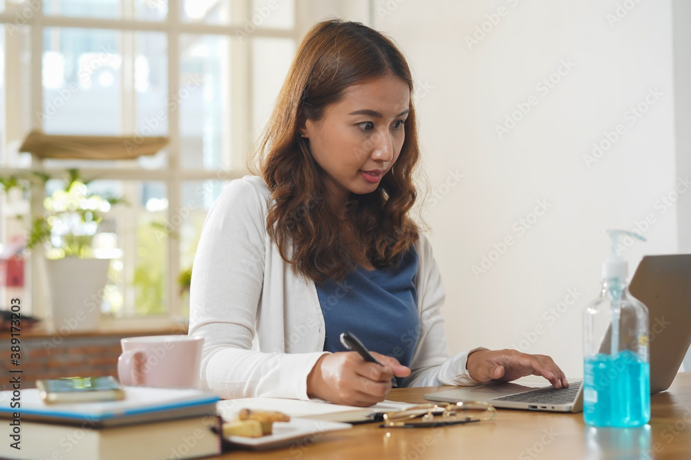 Asian people study online course via internet. Young girl watching business lesson from laptop computer and note lecture to notebook at home. Asian people study online course via internet. Young girl watching business lesson from laptop computer and note lecture to notebook at home.