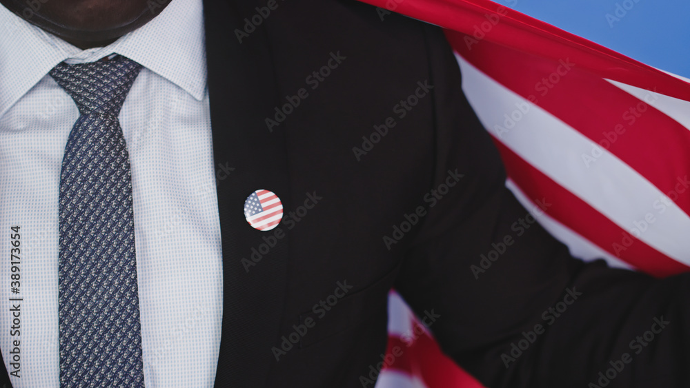 unrecognizable young african american black man in formalwear with usa badge on the chest holding usa flag. High quality photo