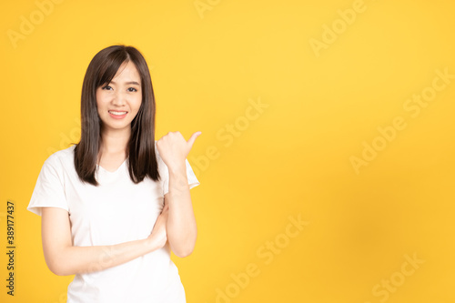 Happy asian young woman wearing white t-shirt standing with present copy space