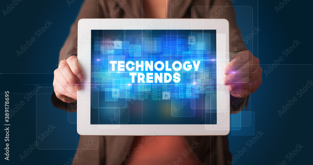 Young business person working on tablet and shows the inscription: TECHNOLOGY TRENDS Young business person working on tablet and shows the inscription: TECHNOLOGY TRENDS