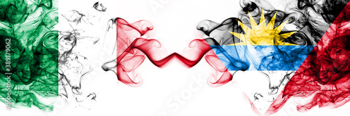 Italy vs Antigua and Barbuda smoky mystic flags placed side by side. Thick colored silky abstract smoke flags