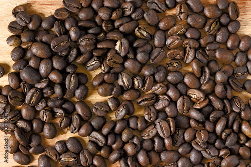 Top down view of spread coffee beans on wooden table. Concept of coffee culture.