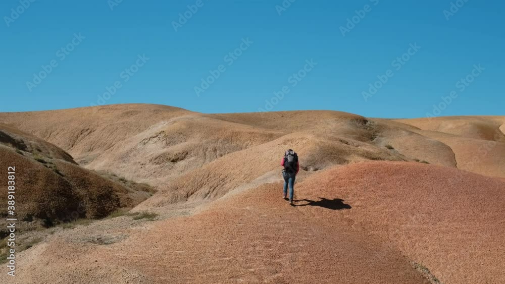 Young Woman Backpacker Climbing a Hill in a Steppe near Mongolian Border. Slow Motion. Recreation, Active Life, Trekking and Traveling Concept Young Woman Backpacker Climbing a Hill in a Steppe near Mongolian Border. Slow Motion. Recreation, Active Life, Trekking and Traveling Concept