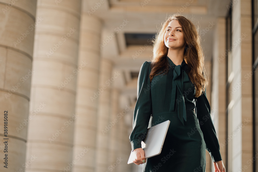 he is holding a laptop with an office folder, working documents, and a project report. smiling in a green dress and looking away. business woman confident teacher management student he is holding a laptop with an office folder, working documents, and a project report. smiling in a green dress and looking away. business woman confident teacher management student