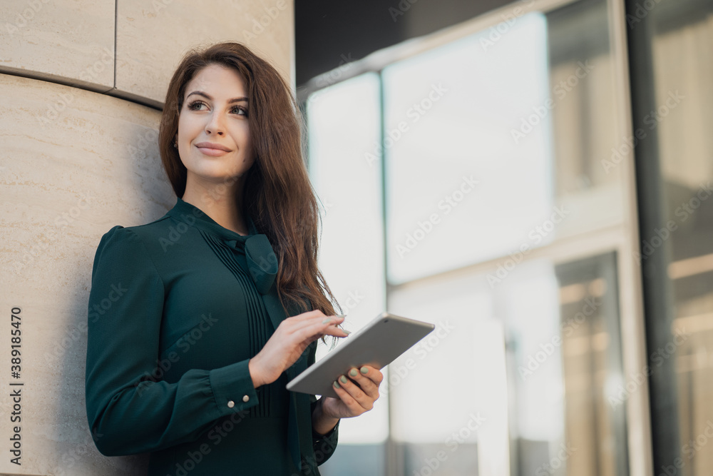 confident woman of European appearance brunette long hair in a new dress. prints the response text message on the tablet in the messenger, sends the partner a report on the work. confident woman of European appearance brunette long hair in a new dress. prints the response text message on the tablet in the messenger, sends the partner a report on the work.