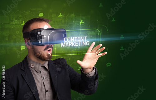 Businessman looking through Virtual Reality glasses with CONTENT MARKETING inscription, social networking concept