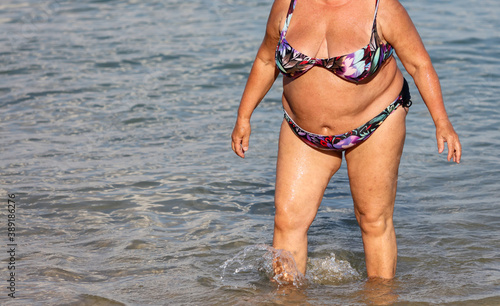 Fat woman in a swimsuit on the seashore.