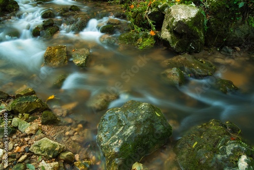 The stream of water in the river flowing between the rocks , long exposure photo